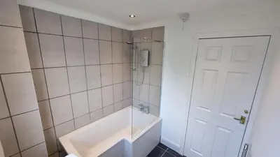 a bathroom with a tub and a white door at Rozelle Villa in Ayr