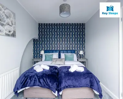 a bedroom with a large bed with blue comforter and white shoes at NEW Four Bedroom House By Keysleeps Short Lets Workington Contractor Leisure Beach Location Lake District in Siddick