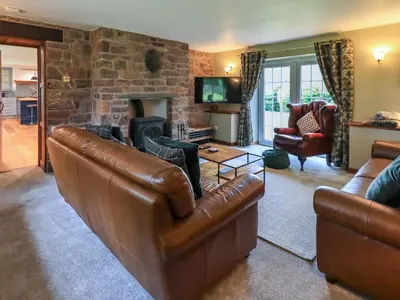 a living room with a leather couch and a fireplace at Flaska House in Penrith