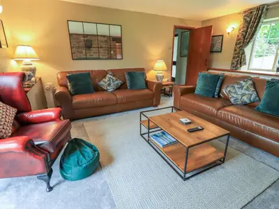 a living room with leather couches and a coffee table at Flaska House in Penrith