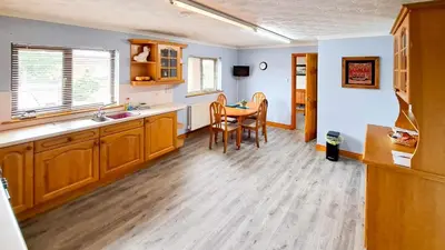 a kitchen with wooden cabinets and a table and chairs at Gretna Getaway in Gretna