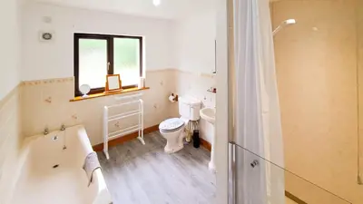 a bathroom with a toilet and a tub and a window at Gretna Getaway in Gretna