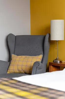 a gray bed with a pillow and a lamp at Bojangles Guest House in Gretna Green