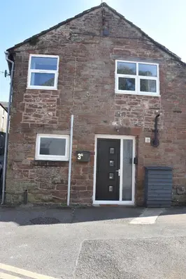 a brick building with a door and two windows at Milo's place is a home from home in Egremont