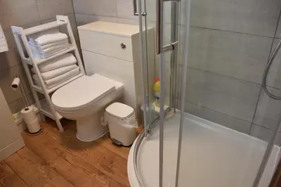 a bathroom with a toilet and a glass shower at Milo's place is a home from home in Egremont
