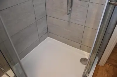 a shower stall with a glass door and a shower at Milo's place is a home from home in Egremont