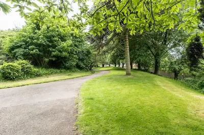 a path in a park with trees and grass at Milo's place is a home from home in Egremont