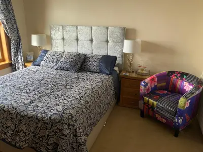 a bedroom with a large bed and a chair at Cairnryan Bed and Breakfast in Cairnryan
