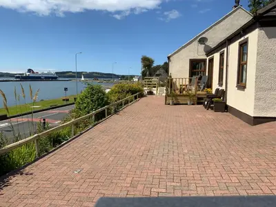 a brick walkway next to a building and a body of water at Cairnryan Bed and Breakfast in Cairnryan