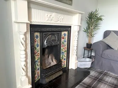 a fireplace in a living room next to a couch at Spacious 3BR Cottage in Beautiful Rural Setting - Pass the Keys in Castle Douglas