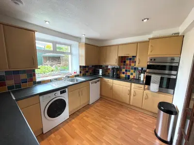 a kitchen with wooden cabinets and a washer and dryer at Spacious 3BR Cottage in Beautiful Rural Setting - Pass the Keys in Castle Douglas