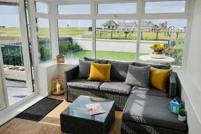 a living room with a couch and a large window at Beautiful Beach Front Cottage in Allonby