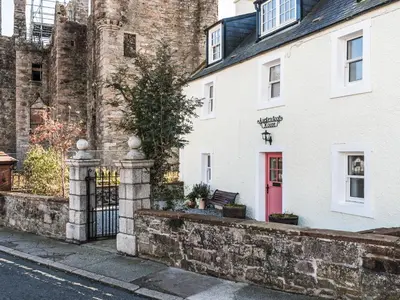 a white building with a red door on a street at Auchengool House in Kirkcudbright