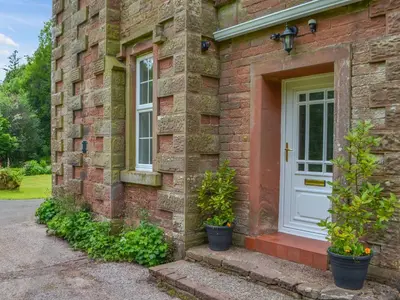 a brick house with a white door and two potted plants at Monkwood Cottage in Hale