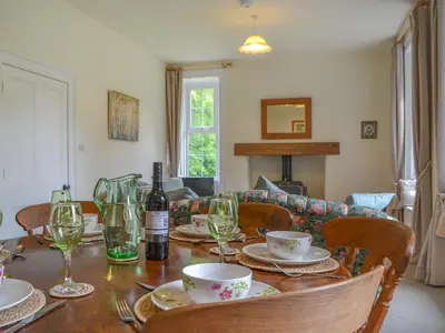 a dining room table with a bottle of wine and glasses at Monkwood Cottage in Hale