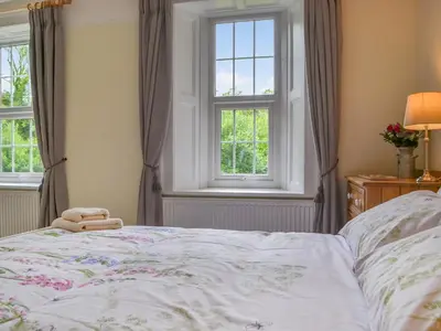 a bedroom with a bed and two windows at Monkwood Cottage in Hale