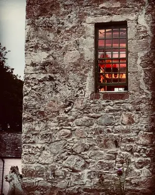 a window of an old stone building with red candles at Buittle Castle Exclusive Use- Stay in your own Castle! in Castle Douglas