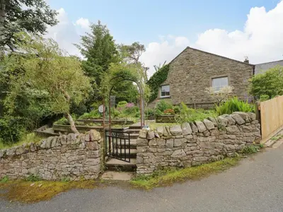 a stone house with a gate and a stone wall at Swaledale Watch House Annexe in Wigton