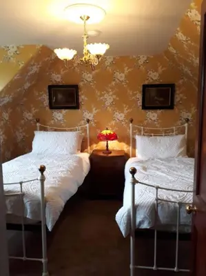 a bedroom with two beds and a chandelier at Beautiful Traditional secluded country cottage in Sanquhar