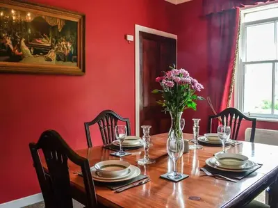 a dining room with a table with a vase of flowers at Beautiful Traditional secluded country cottage in Sanquhar