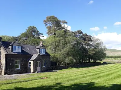 an old stone house on a grassy field at Beautiful Traditional secluded country cottage in Sanquhar