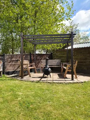 a dog walking in front of a picnic table and a bench at Rooms at the Bush in Wigton