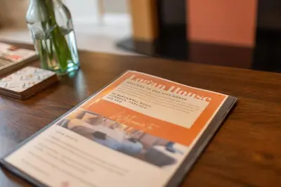a book on a wooden table with a bottle of wine at Logan House, Modern and Spacious Townhouse close to City Centre in Carlisle