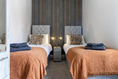 a room with two beds with orange sheets at Logan House, Modern and Spacious Townhouse close to City Centre in Carlisle