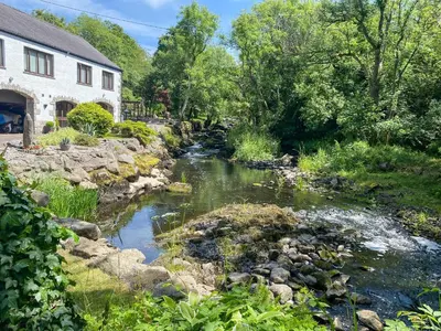 a river next to a house and a building at Forge Mill Cottage in Dalbeattie
