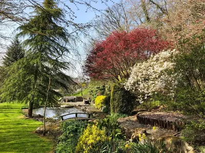 a garden with a pond and a bridge and flowers at Forge Mill Cottage in Dalbeattie