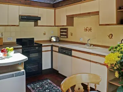 a kitchen with a sink and a chair in it at Forge Mill Cottage in Dalbeattie