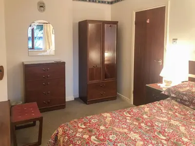 a bedroom with a bed and a dresser and a cabinet at Forge Mill Cottage in Dalbeattie