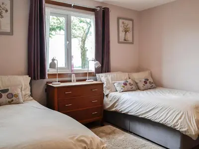 a bedroom with two twin beds and a window at High Threave Cottage in Newton Stewart