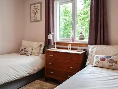 a bedroom with two beds and a window at High Threave Cottage in Newton Stewart