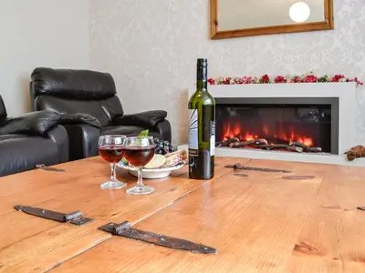 a bottle of wine and two glasses on a wooden table at High Threave Cottage in Newton Stewart