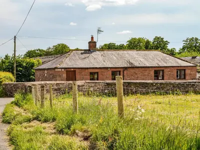an old brick house with a fence in front of it at Low Moat in Canonbie