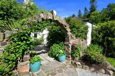 a stone archway with two blue pots of plants at Craigadam Lodge with Hot tub in Castle Douglas