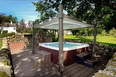 a hot tub under an umbrella on a deck at Craigadam Lodge with Hot tub in Castle Douglas
