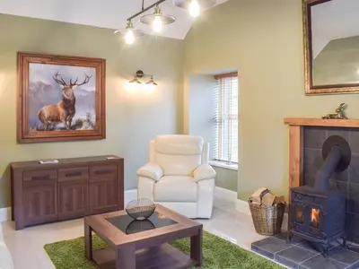a living room with a wood stove and a chair at Dairy Cottage - Uk39522 in Maybole