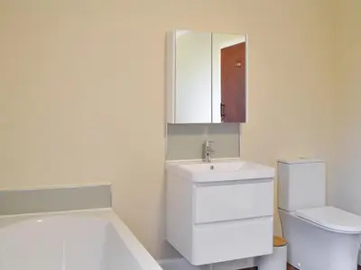 a bathroom with a sink and a toilet and a mirror at Cairncroft Cottage in Colfin