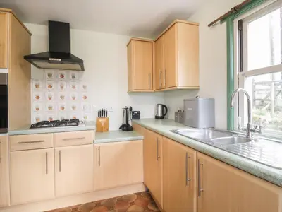 a kitchen with wooden cabinets and a sink and a window at Shaw Cottage in Dumfries