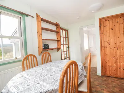 a room with a table and chairs and a window at Shaw Cottage in Dumfries