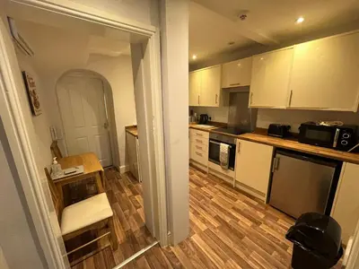 a kitchen with white cabinets and a wooden floor at Petteril House - Ground Floor in Carlisle