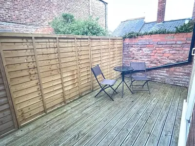 a patio with two chairs and a table on a wooden deck at Petteril House - Ground Floor in Carlisle