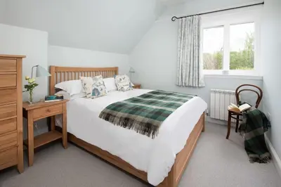 a bedroom with a bed and a desk and a window at Beltie Lodge in Borgue