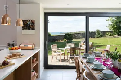 a kitchen with a table and a dining room with a view at Beltie Lodge in Borgue