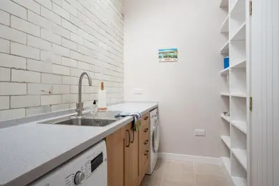 a kitchen with a sink and a white brick wall at Beltie Lodge in Borgue