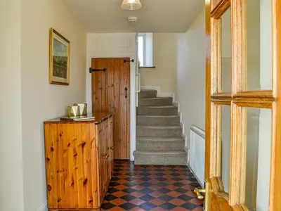 a hallway with a staircase and a wooden door at Mullhill in Ardwell