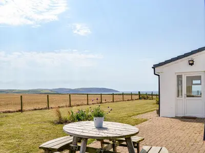 a picnic table in front of a building with a field at Mullhill in Ardwell
