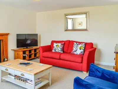 a living room with a red couch and a tv at Mullhill in Ardwell